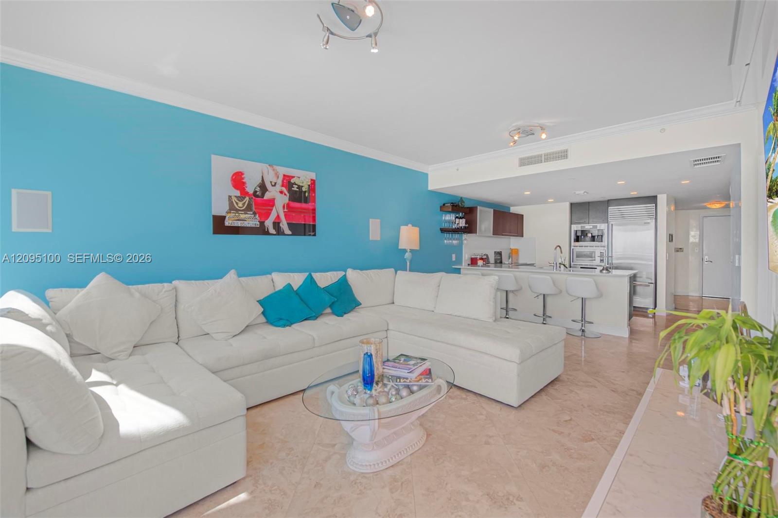 Open living room with a white sectional and turquoise accent wall beside a kitchen island.