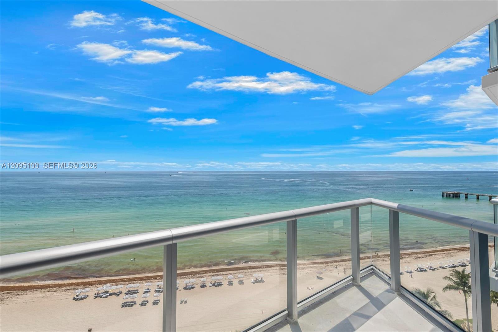 Oceanfront balcony overlooking turquoise water and a sandy beach.