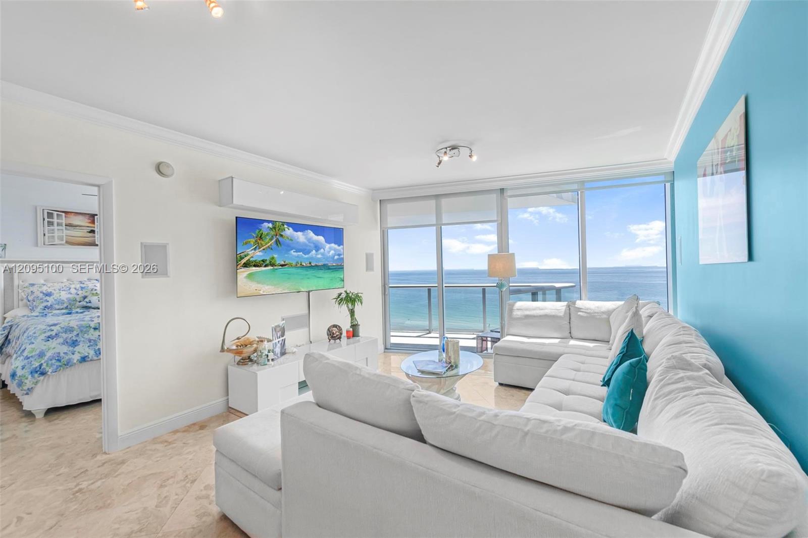 Furnished living room with a white sectional and floor-to-ceiling ocean-view windows.