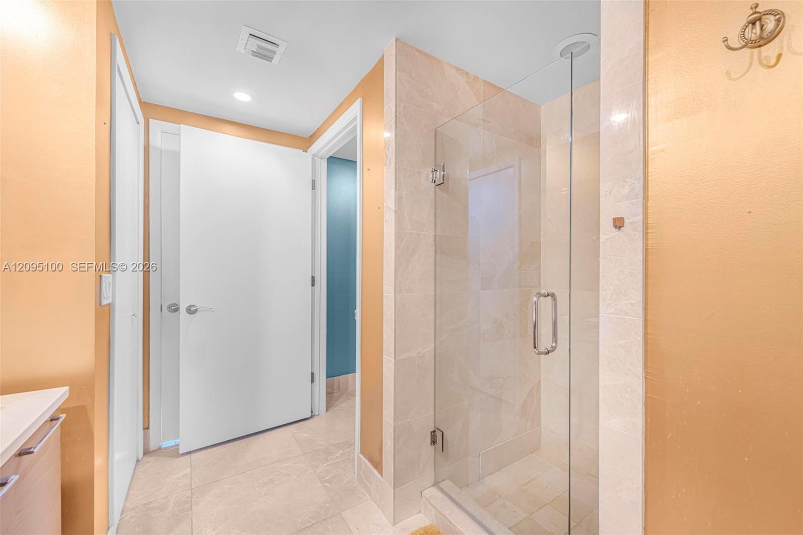 Bathroom with a glass-enclosed walk-in shower and pale stone tile.