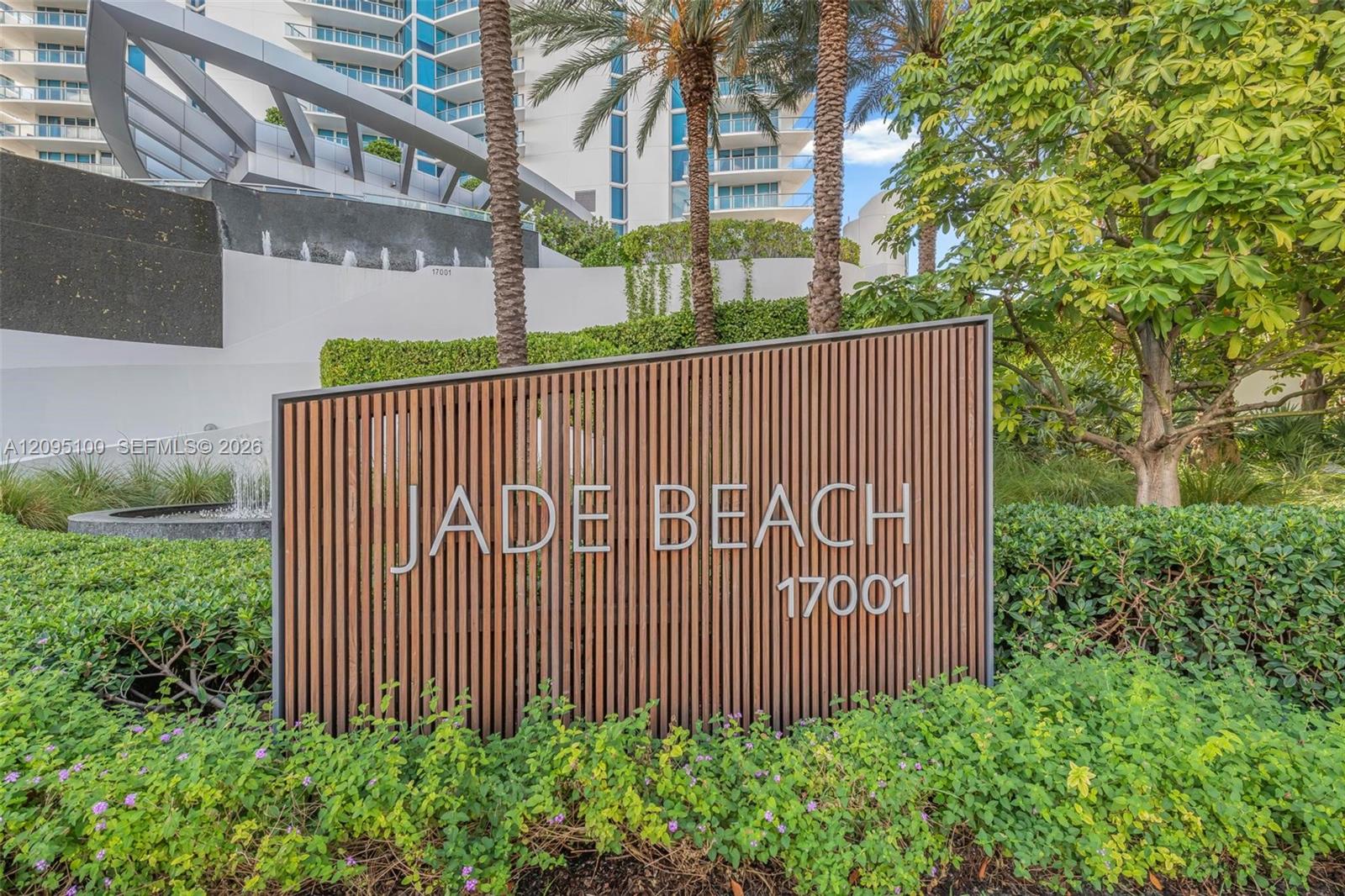 Jade Beach condominium entrance with its 17001 sign, fountain, palms, and landscaped grounds.