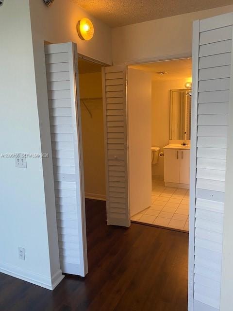Open louvered closet doors frame a tiled bathroom with a vanity and toilet.