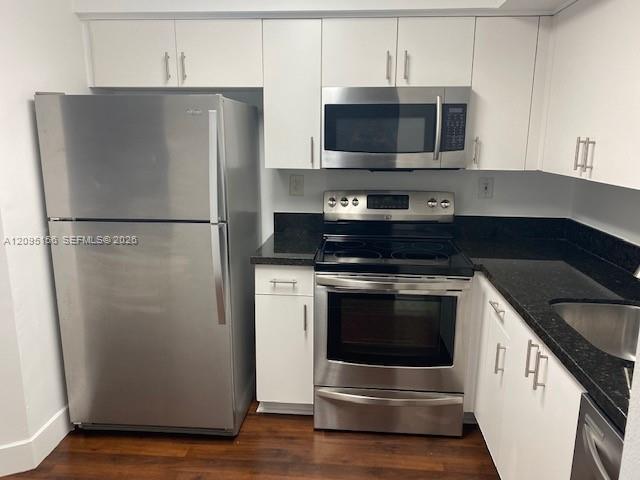 Kitchen with white cabinets, dark granite counters, and stainless steel appliances.