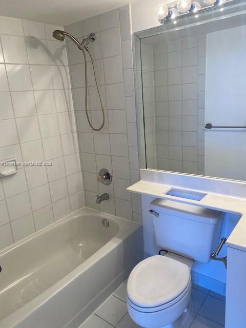 Bathroom with a white tub, handheld shower, toilet, and large mirror.