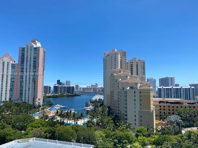 Waterfront high-rises and marina beneath a clear blue sky.