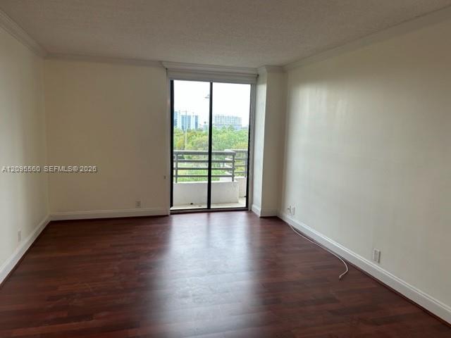 Empty room with dark wood floors and sliding glass doors opening to a balcony.