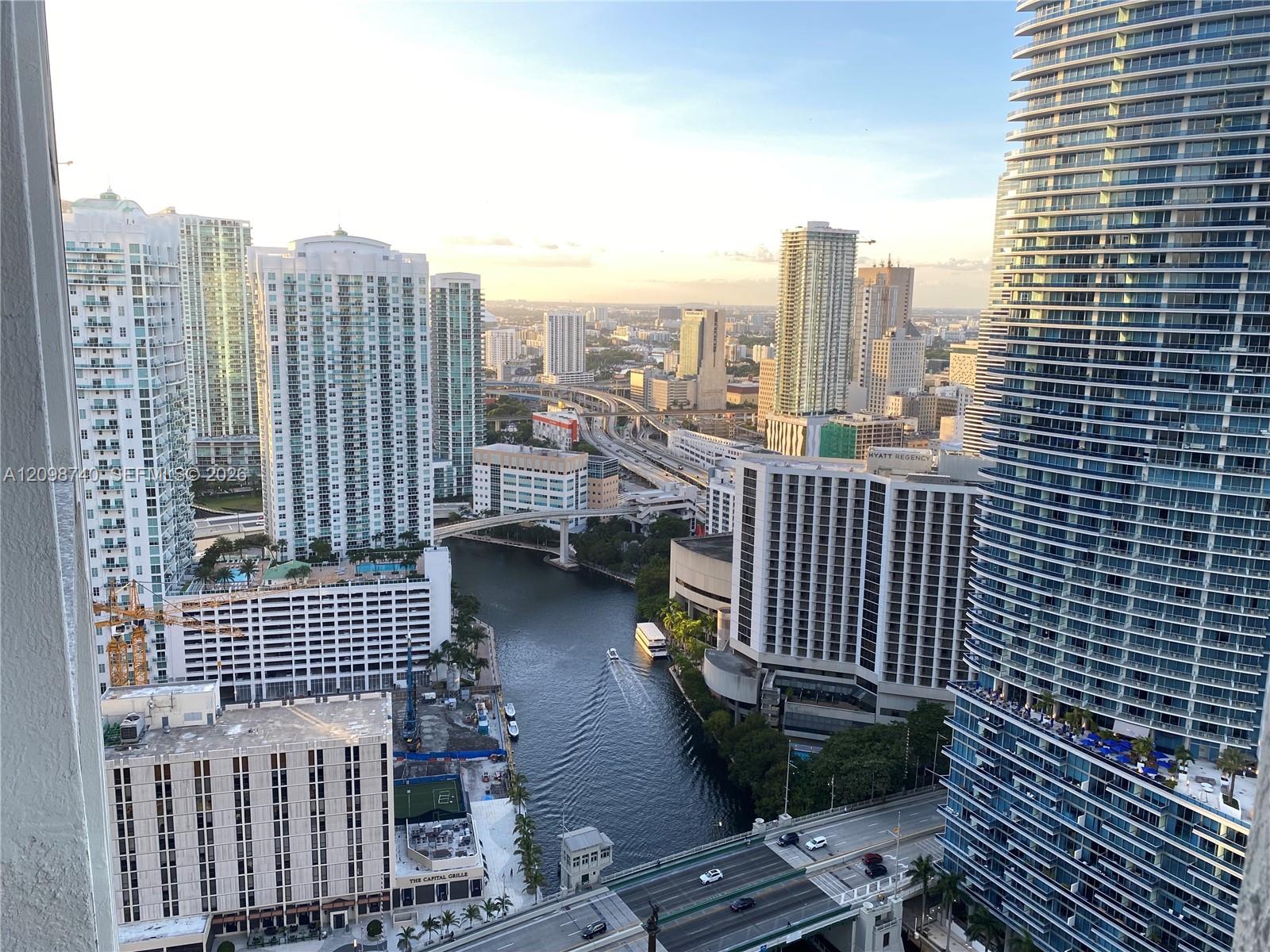 High-rise view over downtown Miami, with a canal, bridges, and surrounding towers.