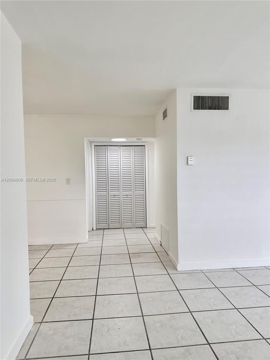 Empty tiled entry hall with white walls and louvered closet doors.