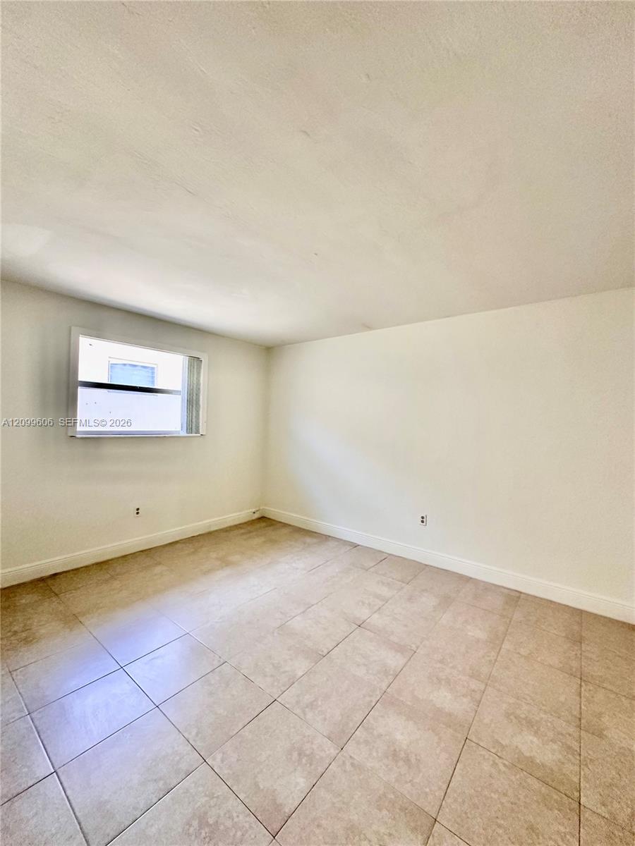 Empty room with beige tile flooring and a small horizontal window.