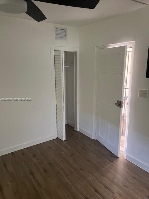 Vacant bedroom with wood-look flooring, ceiling fan, and louvered closet doors.