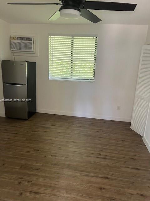 Unfurnished room with wood-look flooring, ceiling fan, refrigerator, and window blinds.