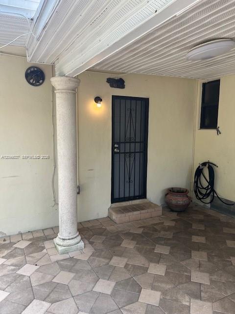 Covered entry with a black security door, tiled floor, and white column.