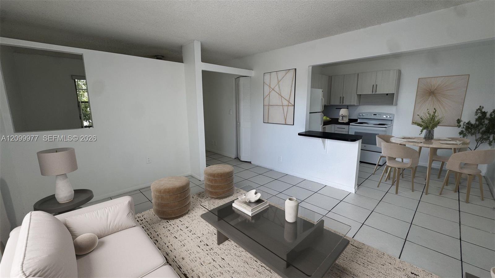 Open-plan condo living room with a light sofa, tiled floors, and kitchen and dining area.