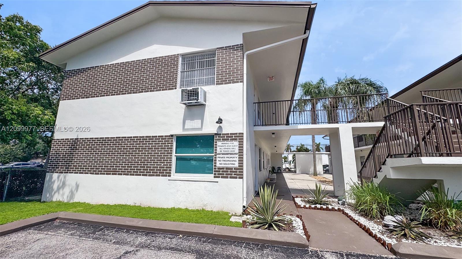 Two-story apartment building with a brick-and-stucco exterior, open breezeway, and exterior staircase.