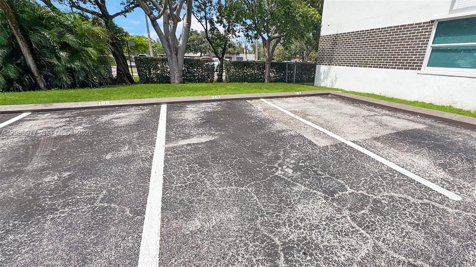 Parking space 207 beside a building, marked on the curb between spaces 105 and 107.