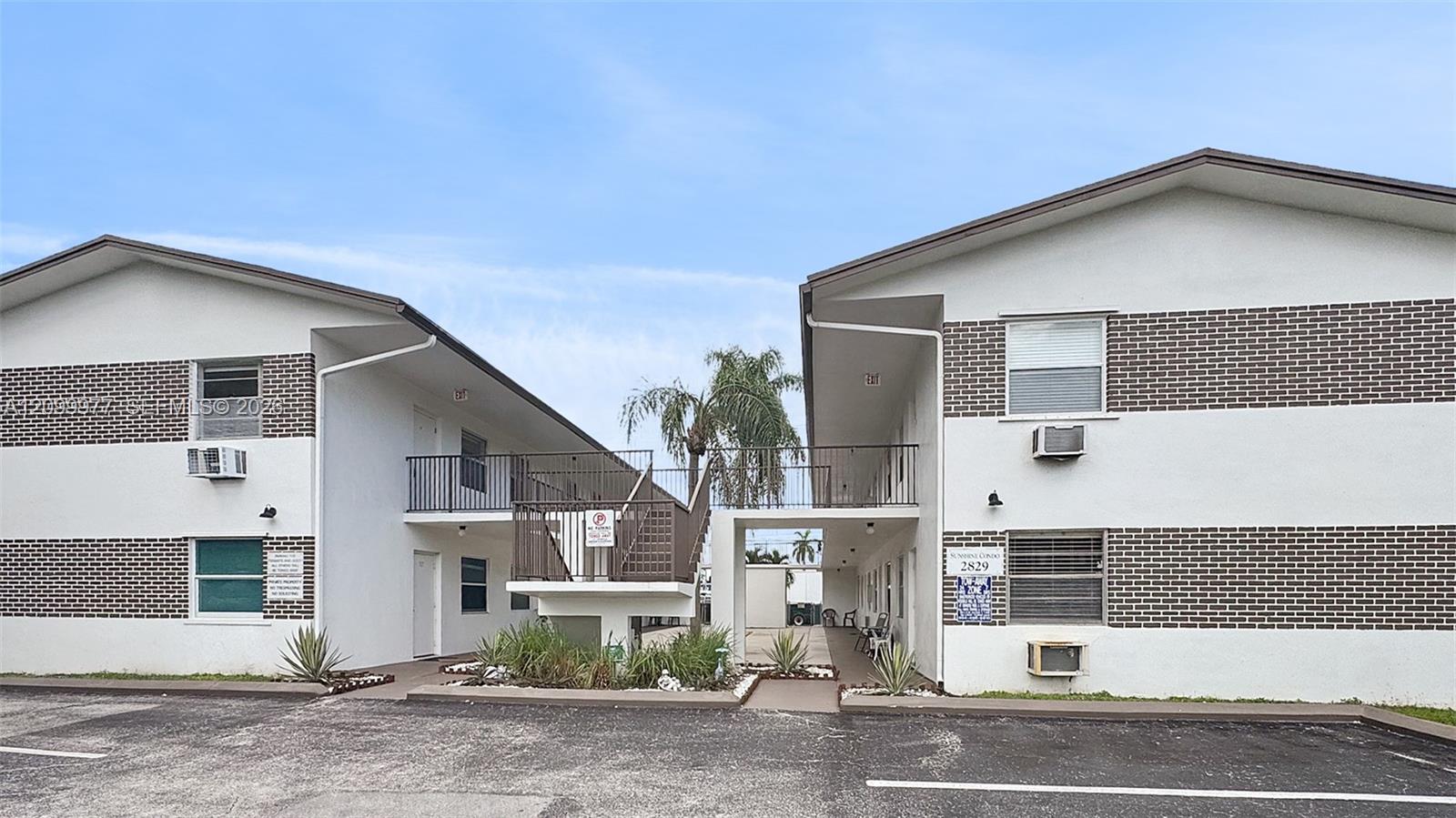Two-story condominium building with brick bands and a central covered passage.