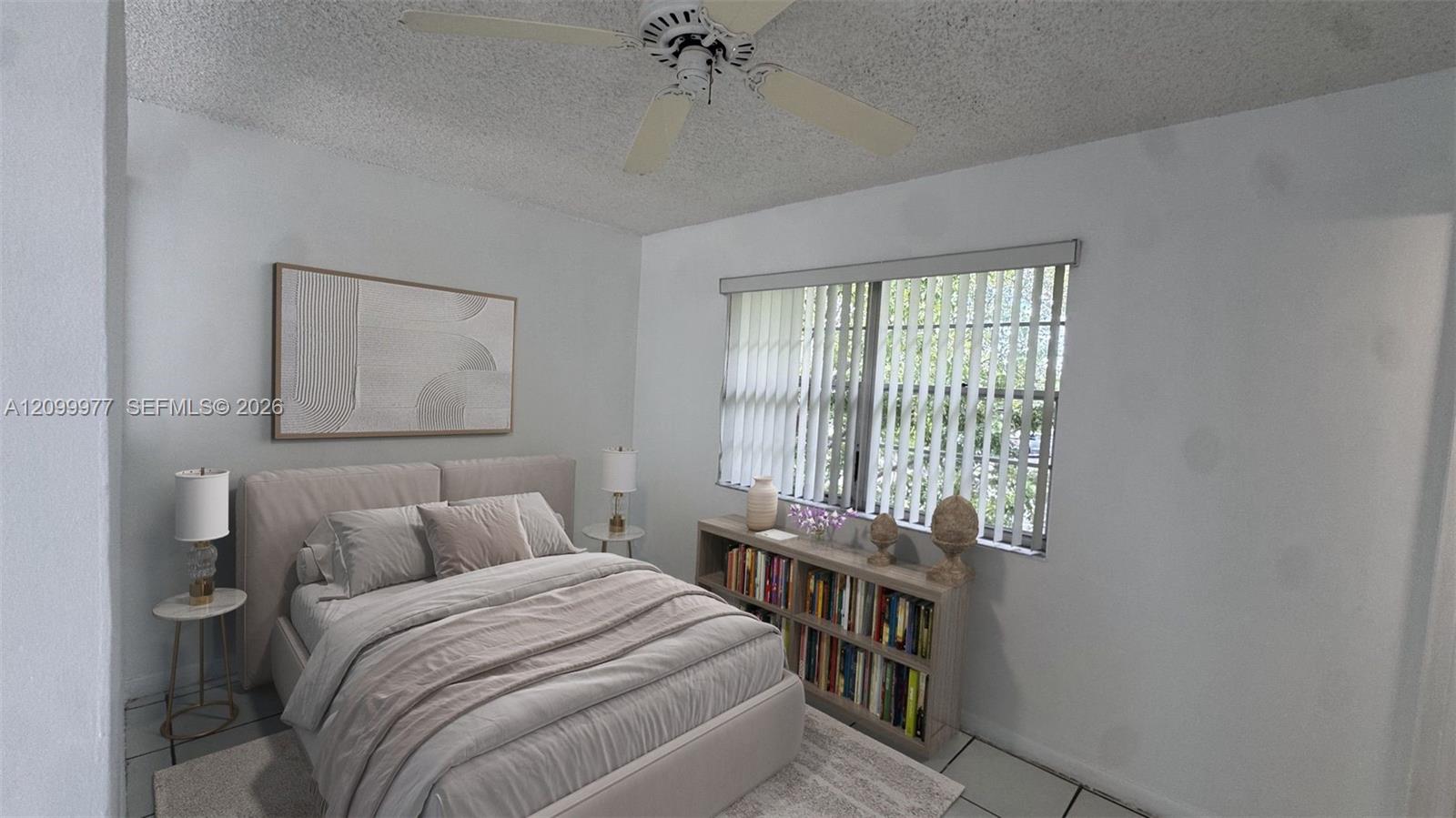Bedroom with a gray upholstered bed and a bookcase beneath a window with vertical blinds.