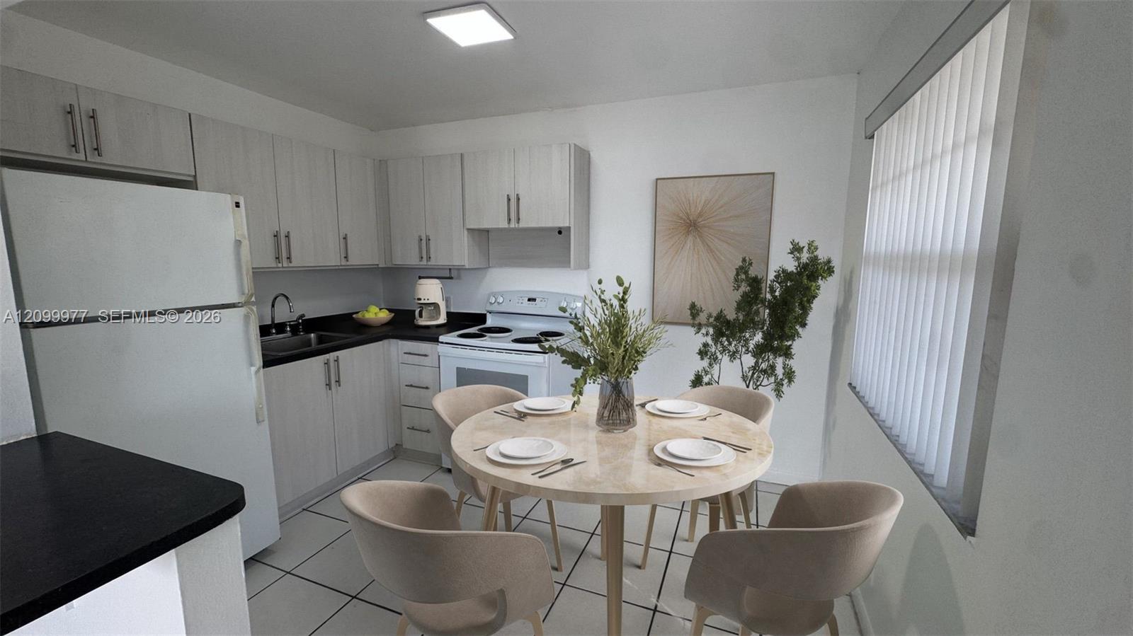 Kitchen and dining area with light cabinets, black countertops, and a round table set for four.