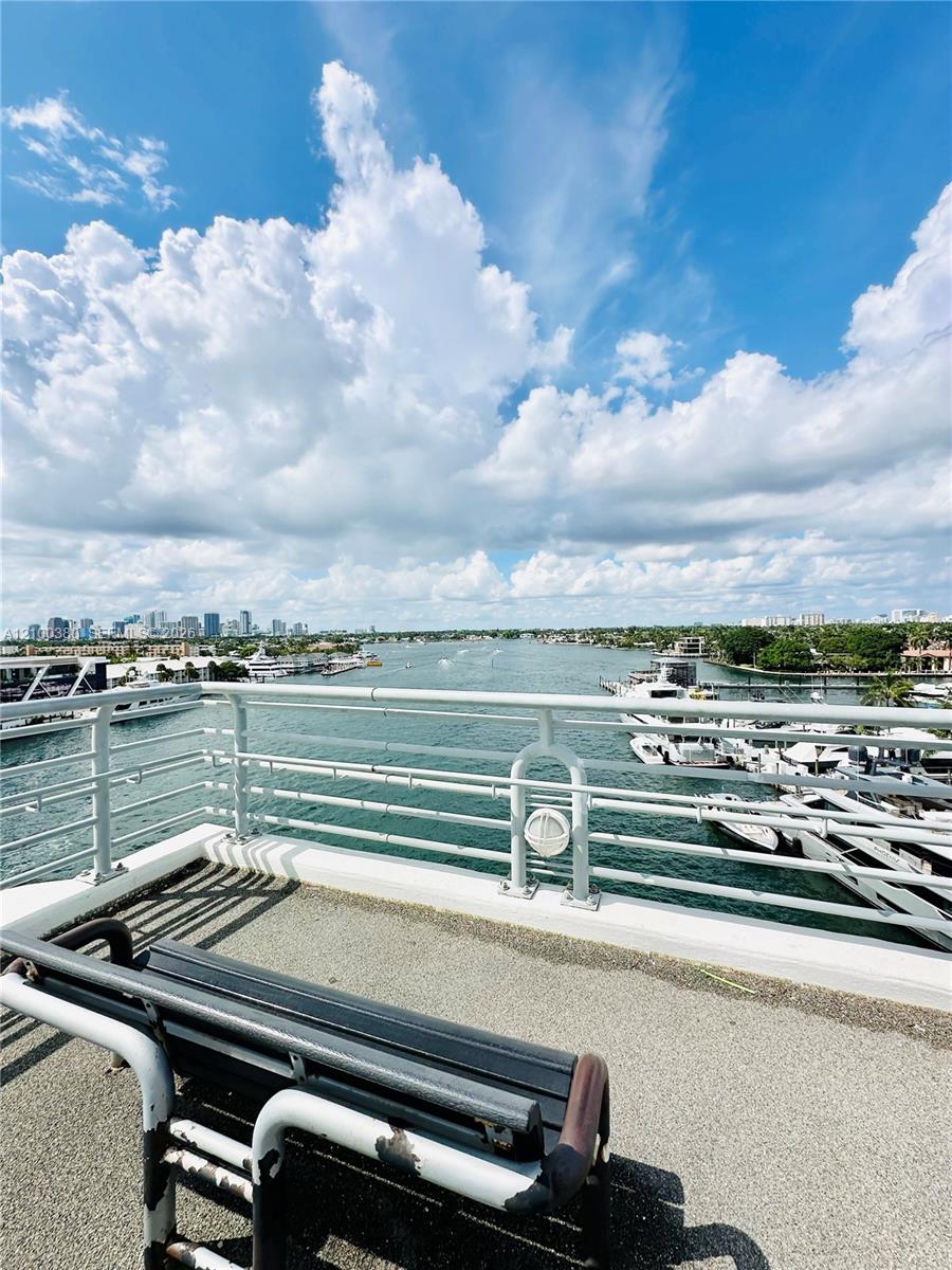Condo balcony overlooking a boat-lined waterway, with a lounge chair in the foreground.