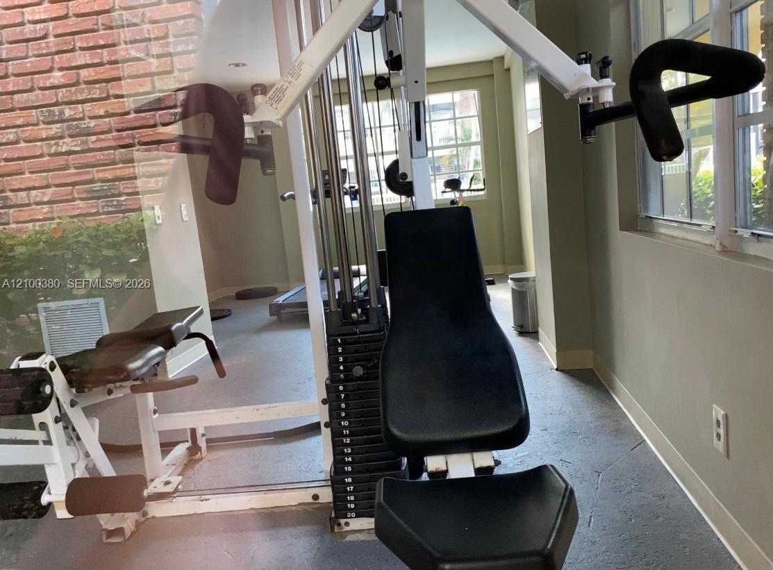 Fitness room with a cable weight machine, other exercise equipment, and bright windows.