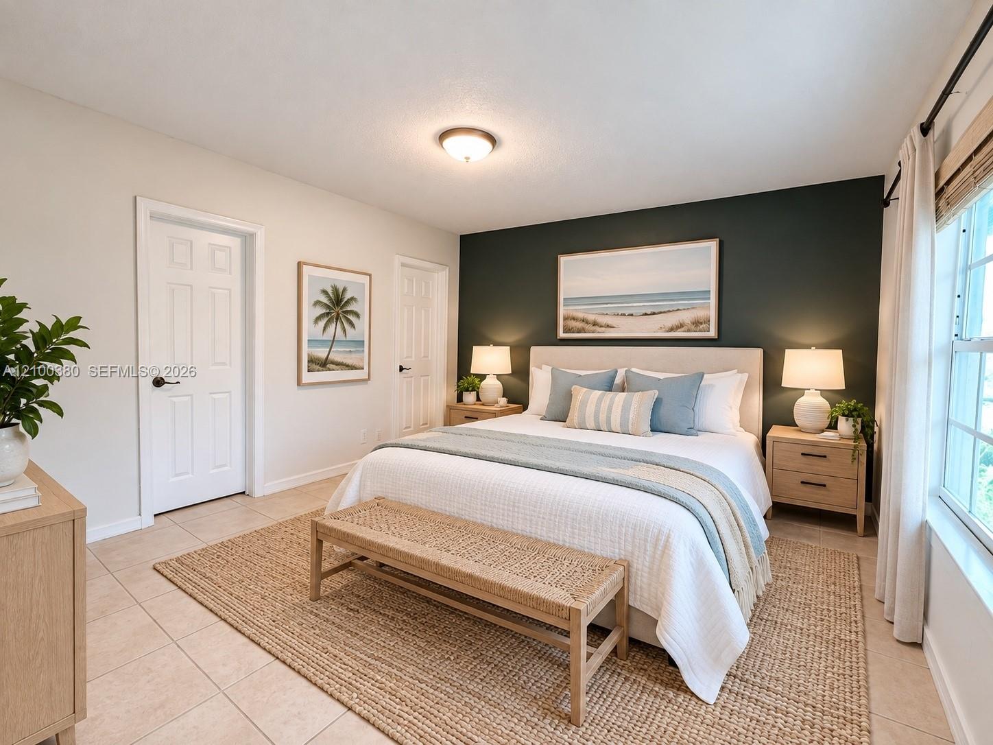 Staged bedroom with a white bed, dark green accent wall, pale blue bedding, and woven bench.