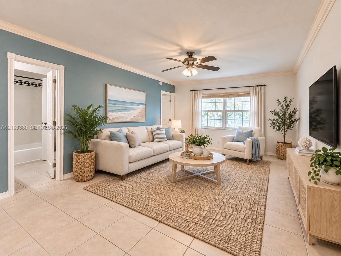Staged living room with a cream sofa, blue accent wall, woven rug, and ceiling fan.