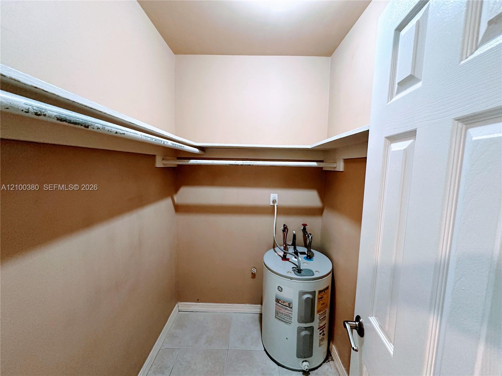 Utility closet with a water heater and wraparound shelves.