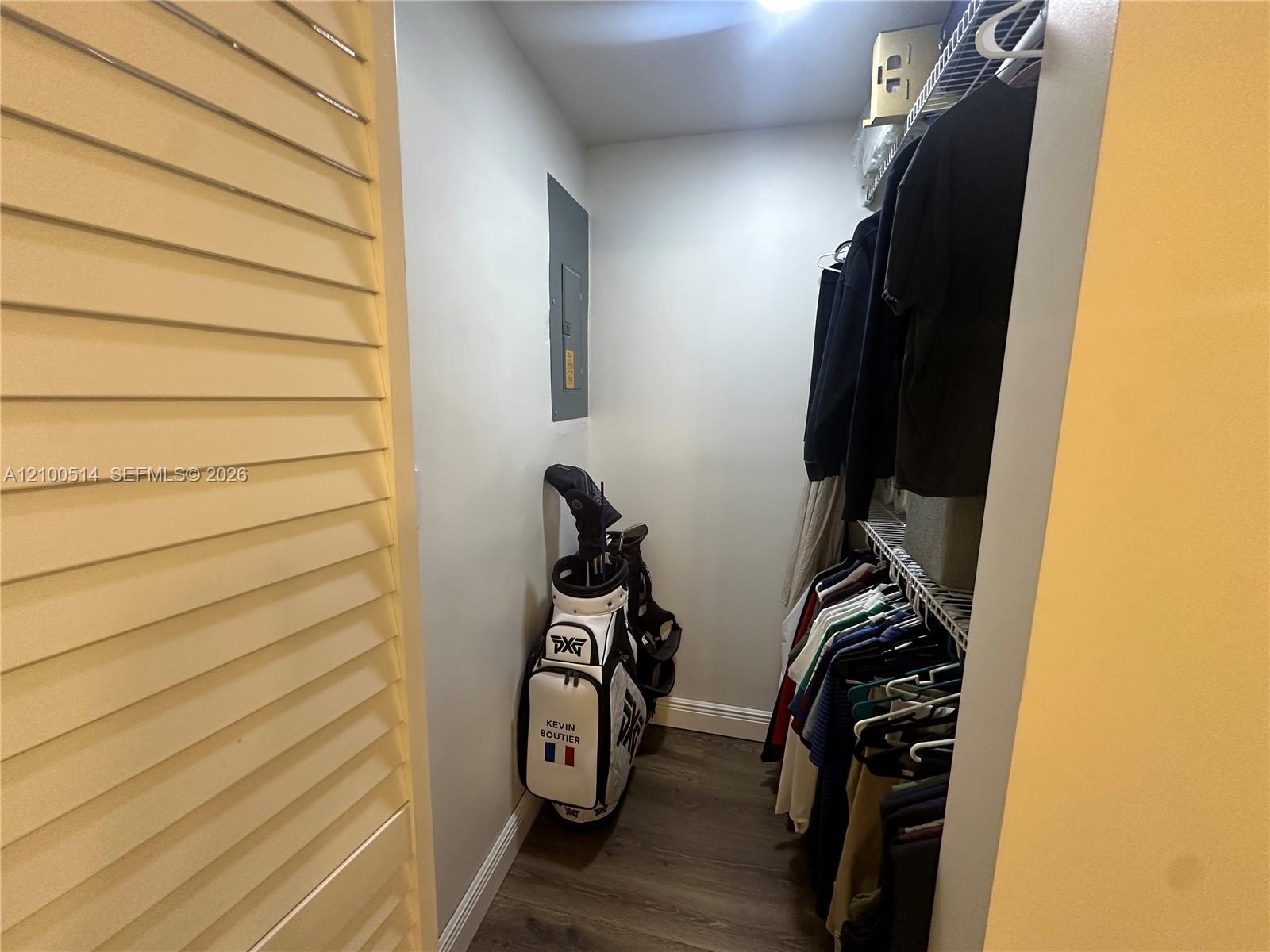 Walk-in closet with wire shelving, hanging clothes, and a golf bag at the back.