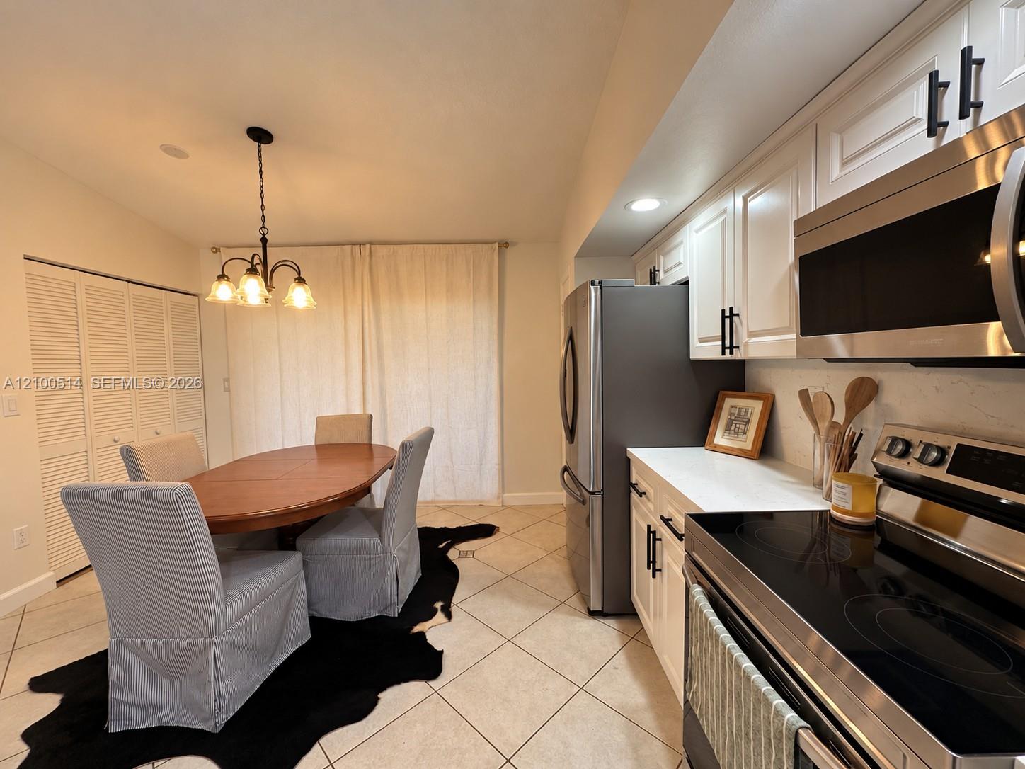 Kitchen and dining area with white cabinets, stainless steel appliances, and a round wooden table.