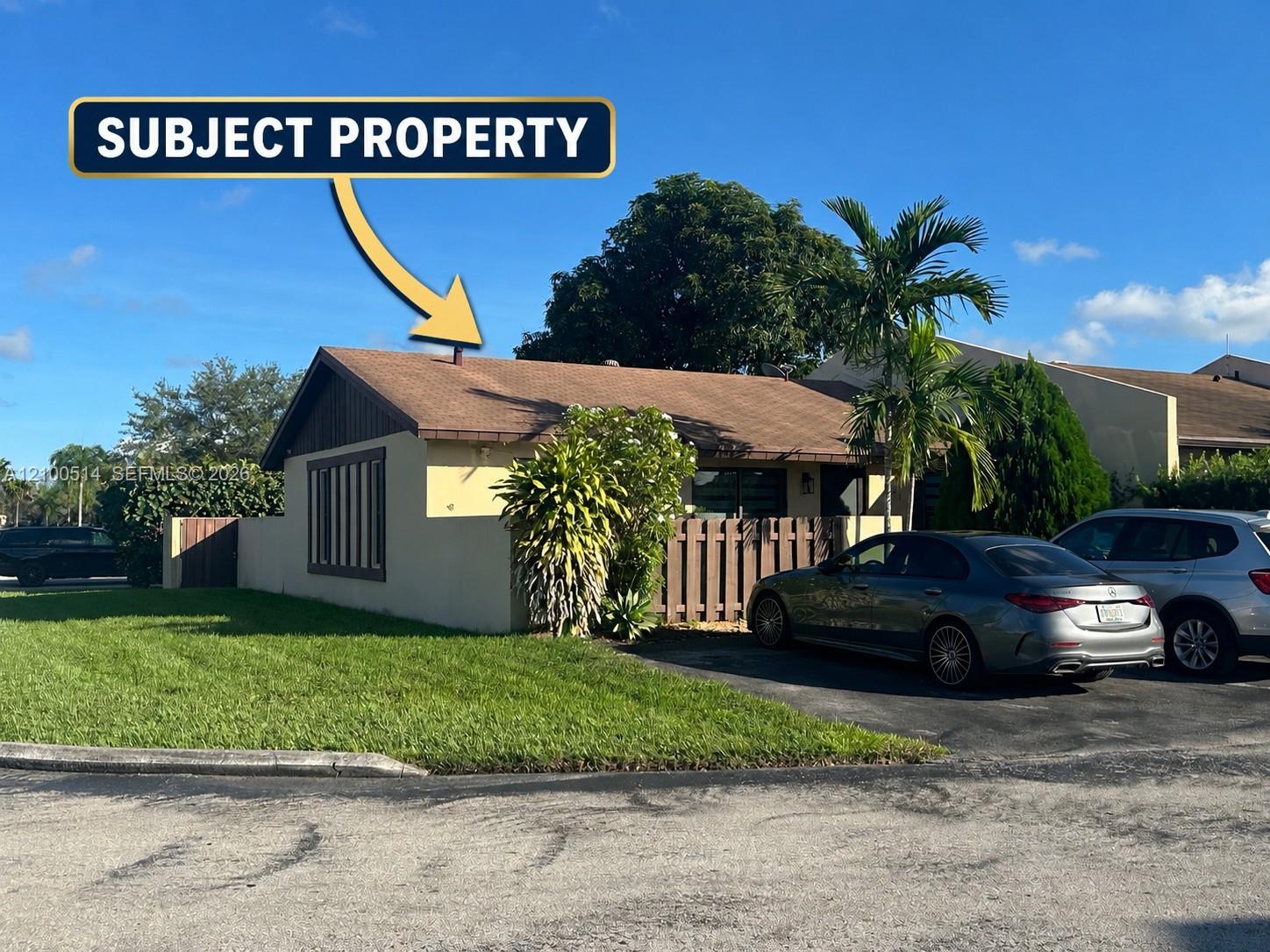 Single-story house with a brown roof, front lawn, and a yellow arrow identifying the property.