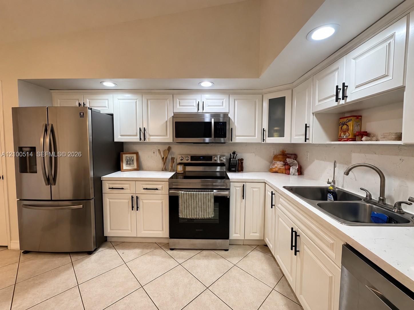 Kitchen with white cabinets, stainless steel appliances, and a double-basin sink.