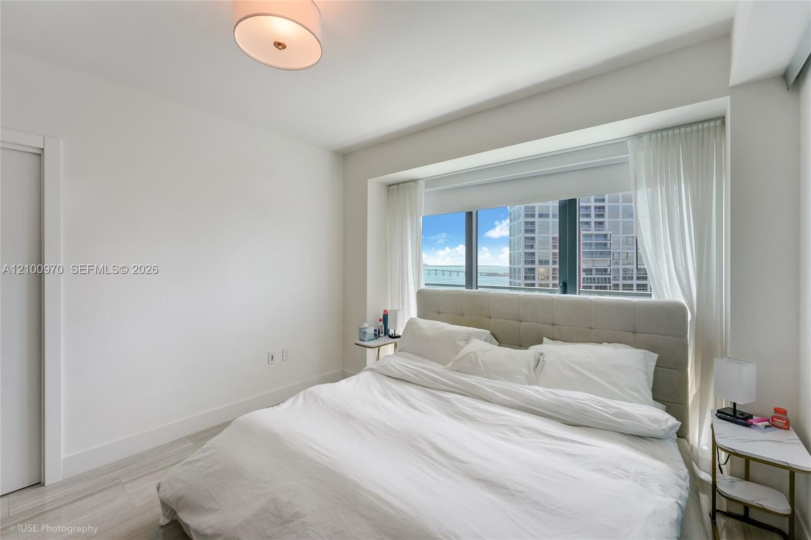 Furnished bedroom with a large bed and bay views through a floor-to-ceiling window.