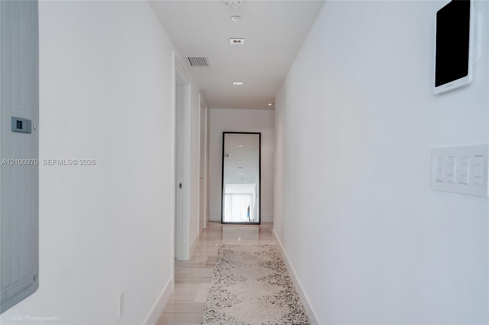 Bright white hallway with a patterned runner rug and full-length mirror.