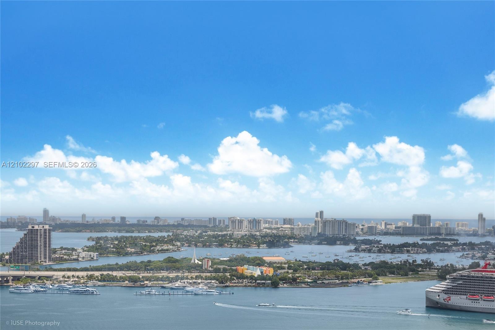 Panoramic Miami bay view with boats, a cruise ship, and the distant city skyline.