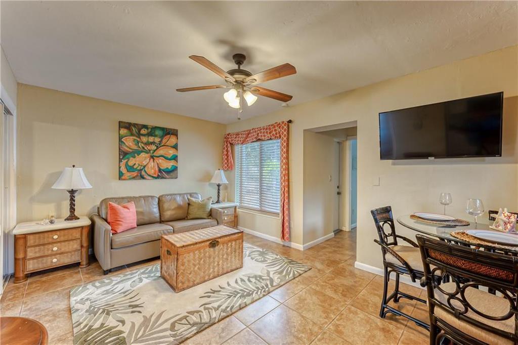 Living room with a leather sofa, patterned rug, and wall-mounted television beside the dining area.