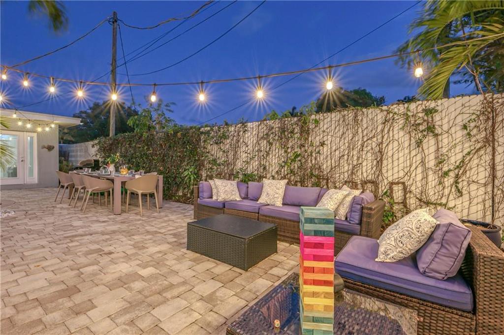 Furnished patio with wicker lounge seating, a dining table, and string lights at dusk.