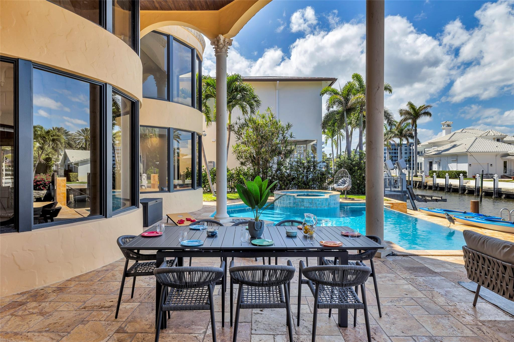 Waterfront patio with outdoor dining set, swimming pool, raised spa, and canal views.