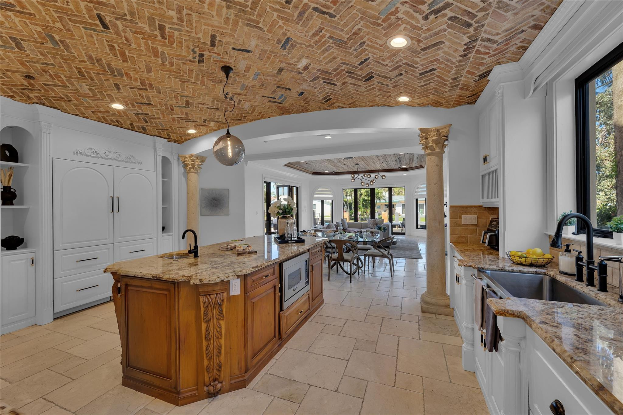 Kitchen with brick ceiling, carved wood island, and view into dining and living areas.