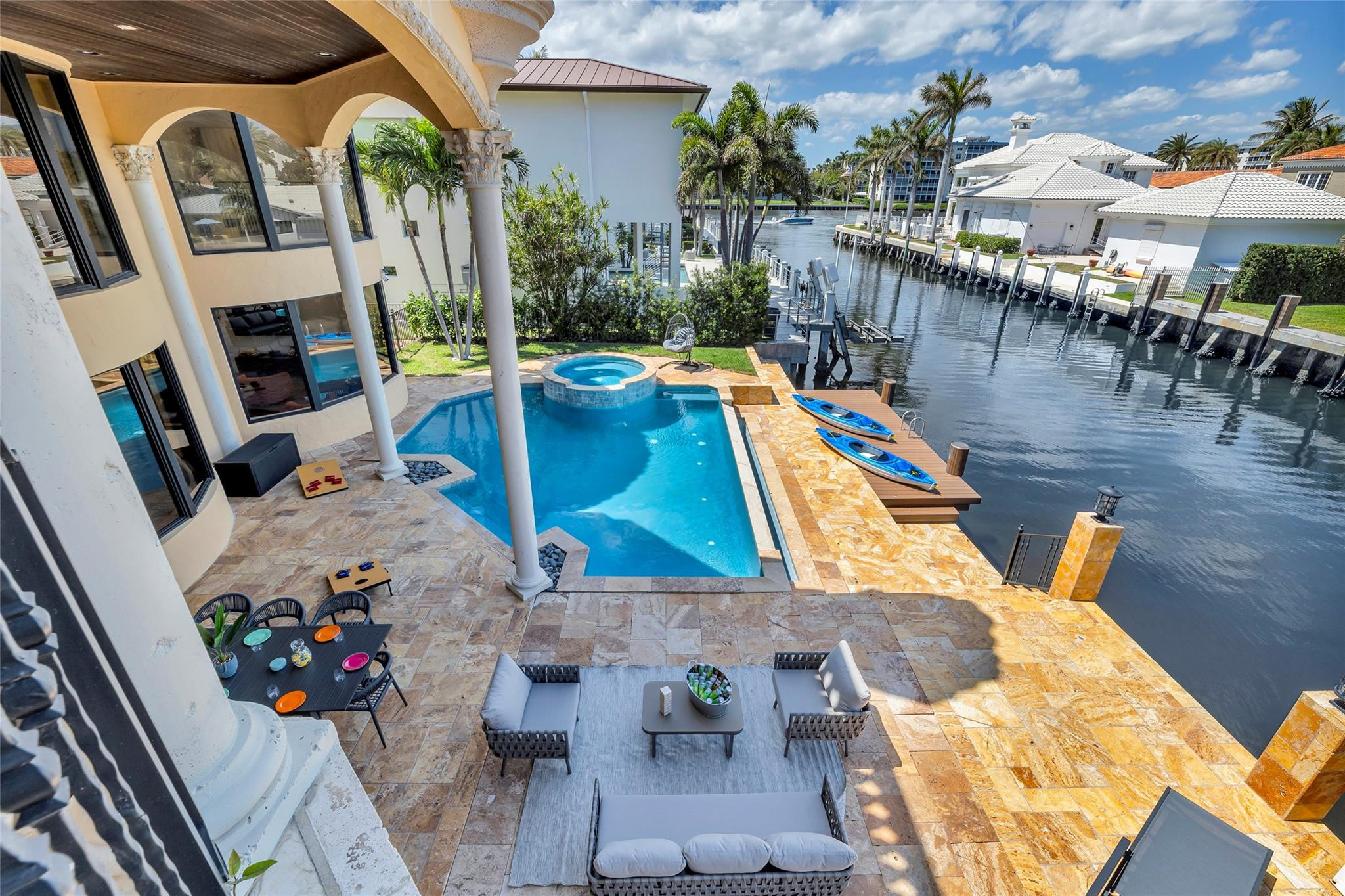 Waterfront patio with a pool, raised spa, canal dock, and two kayaks.