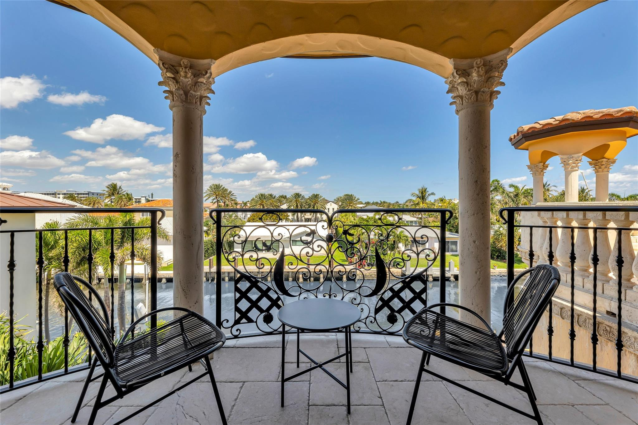 Covered balcony with ornate columns and wrought-iron railings overlooking a canal.