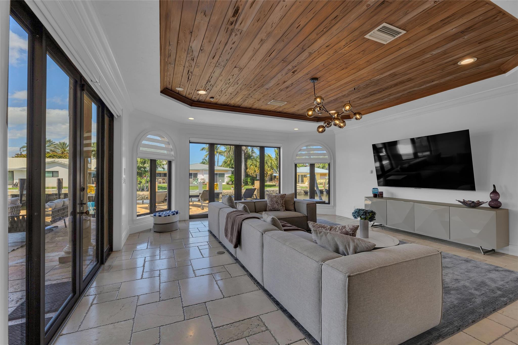 Living room with a large sectional, wood-plank ceiling, and glass doors opening to a patio.