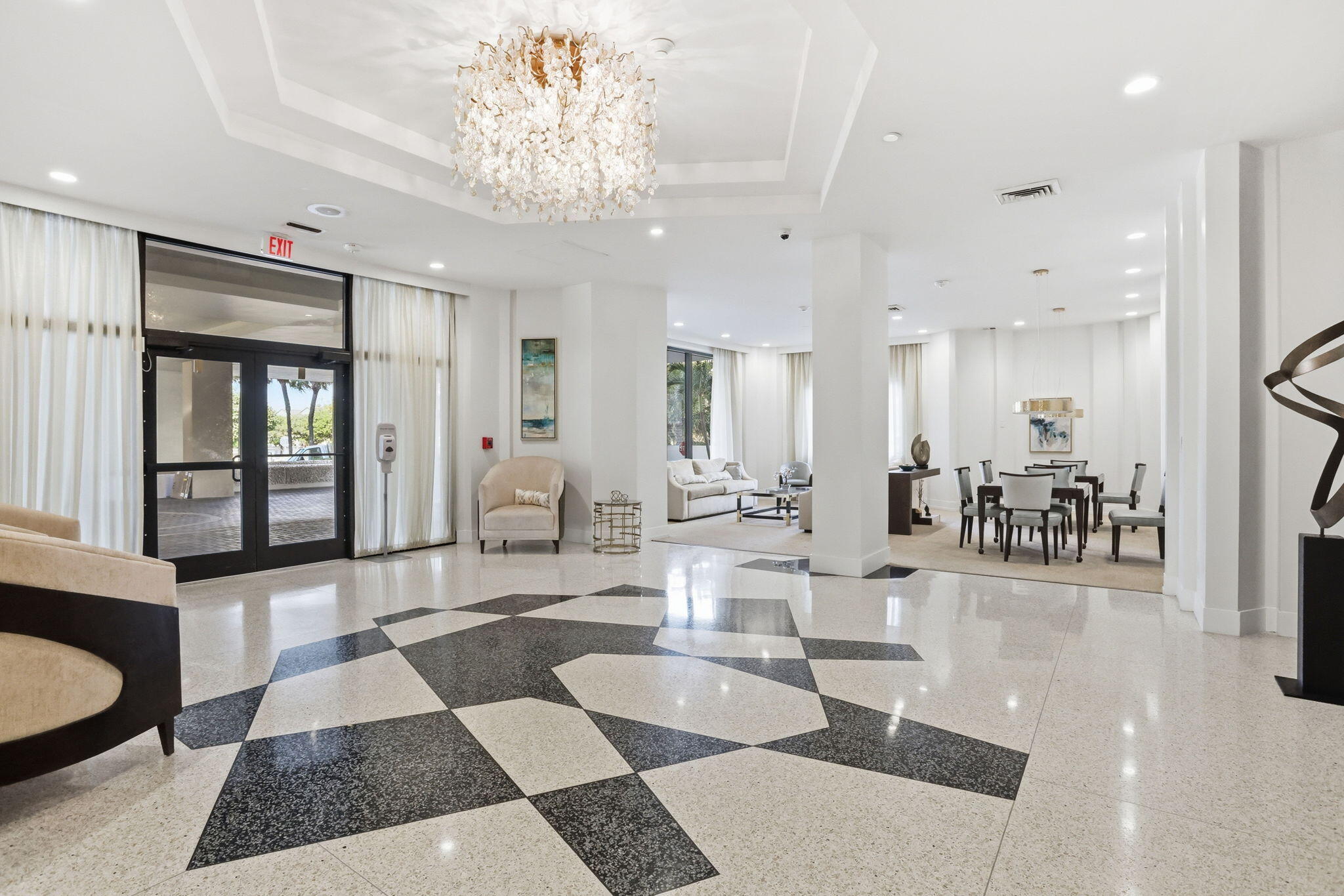 Furnished condominium lobby with a crystal chandelier and geometric black-and-cream stone floor.