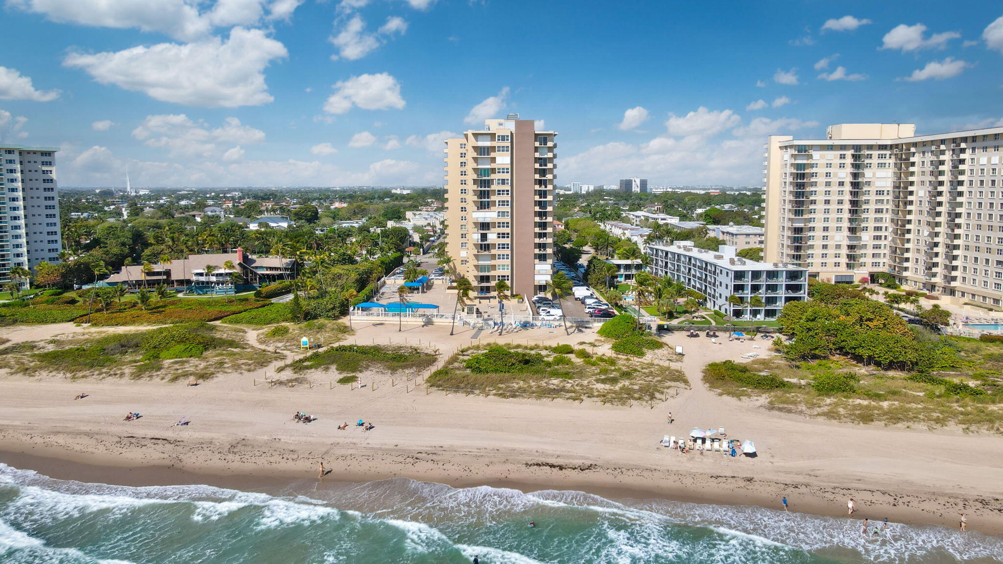 Beachfront condominium buildings beside a sandy beach and ocean.