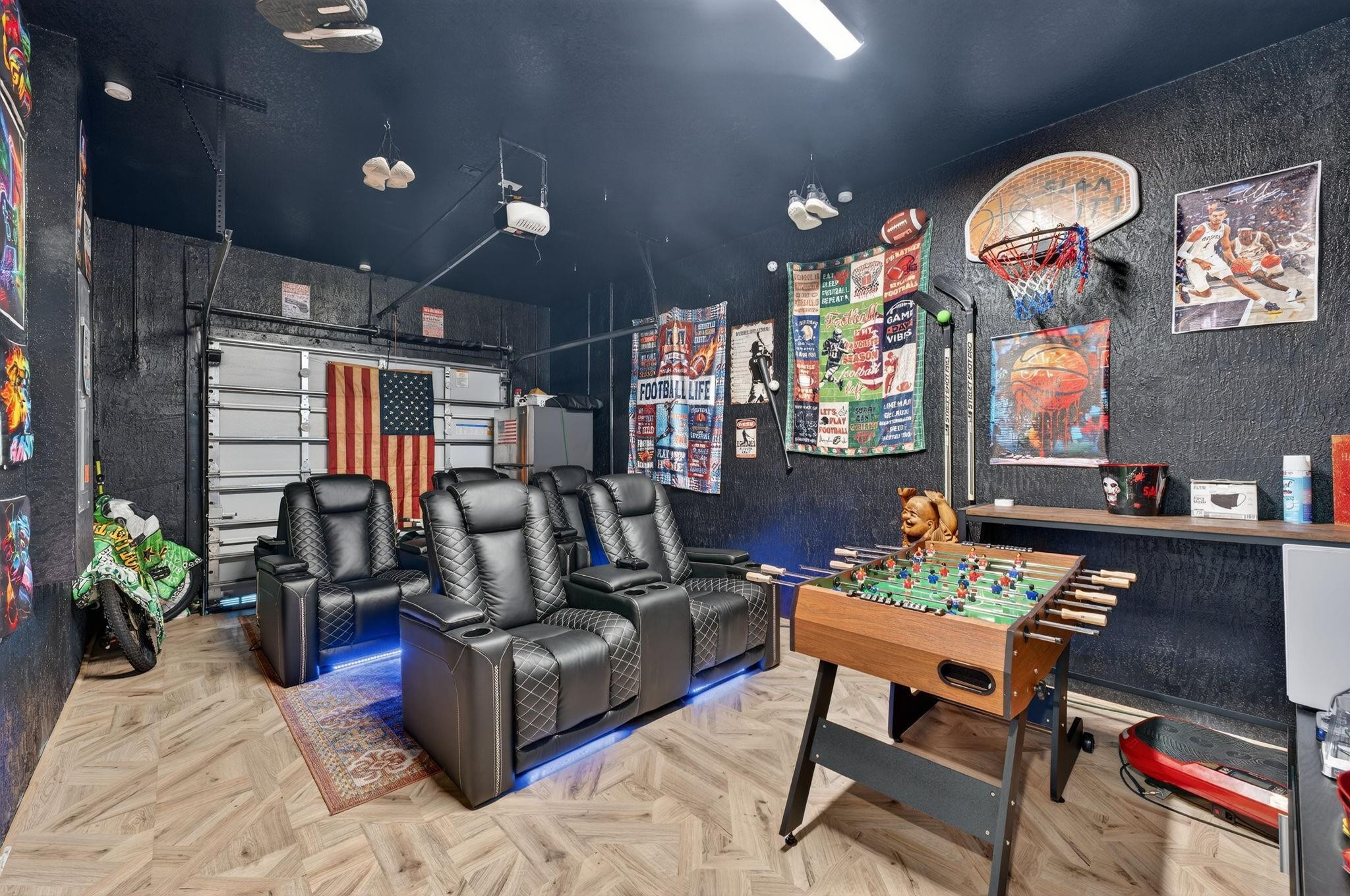 Game room with three leather theater recliners, a foosball table, and a basketball hoop.