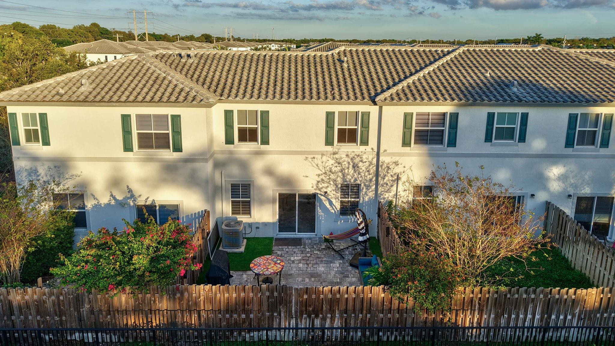 Rear of a two-story home with a fenced patio, pavers, and a hammock.
