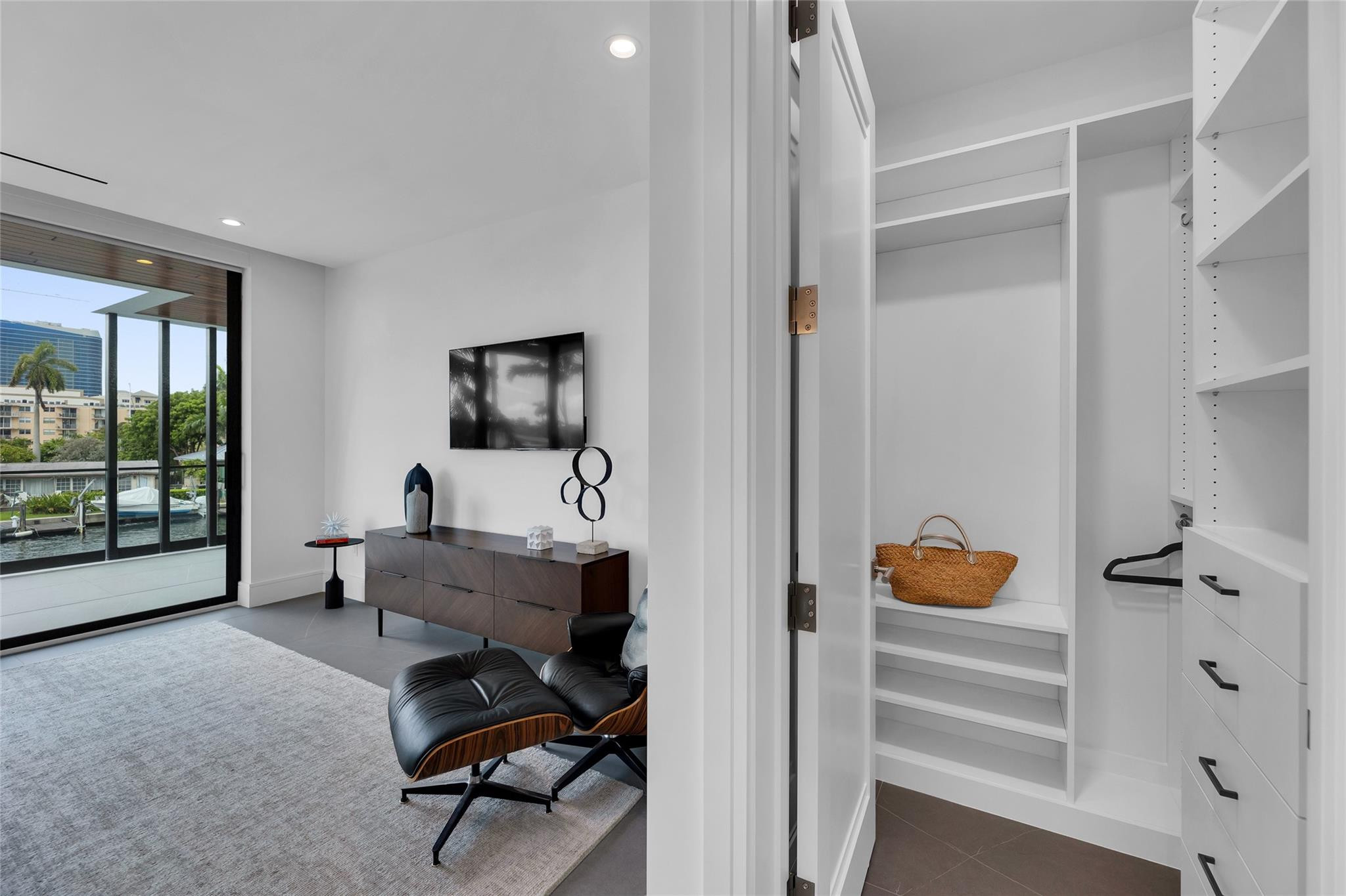 Modern living room and built-in walk-in closet, with a leather lounge chair beside canal-facing glass doors.