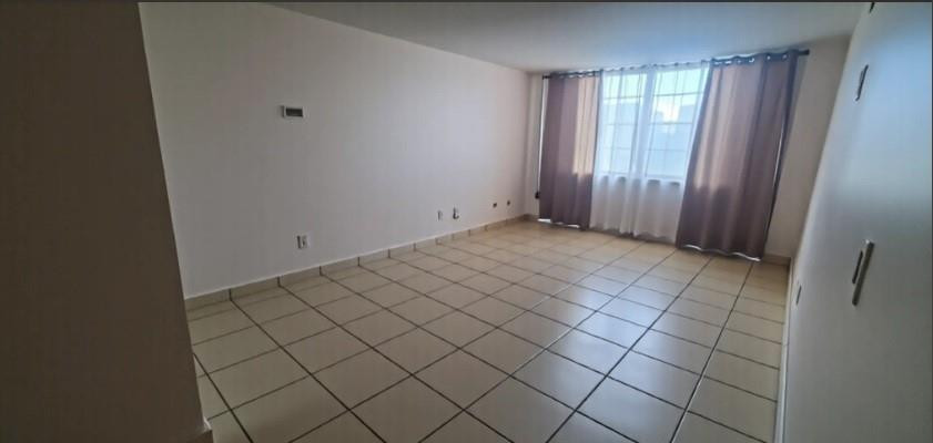 Empty tiled room with a curtained window letting in daylight.