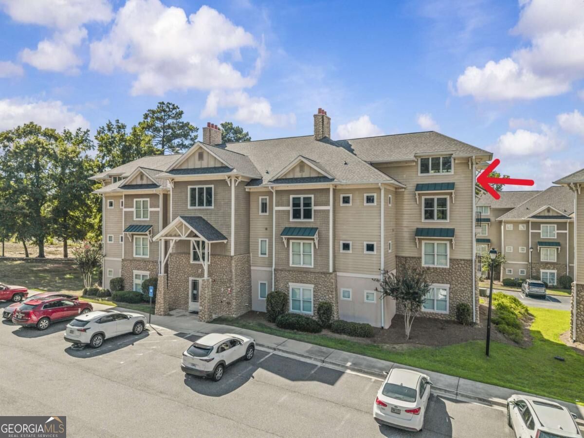 Multi-unit residential building with stone accents and a red arrow pointing to an upper-floor unit.