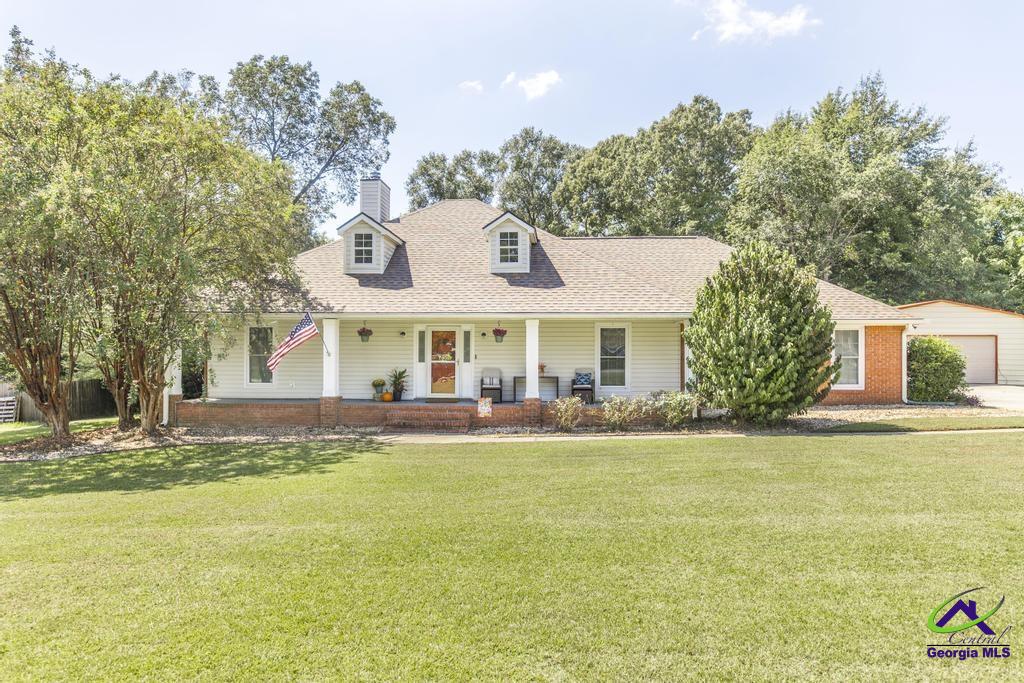 Ranch-style home with a covered porch, two dormers, and a broad front lawn.