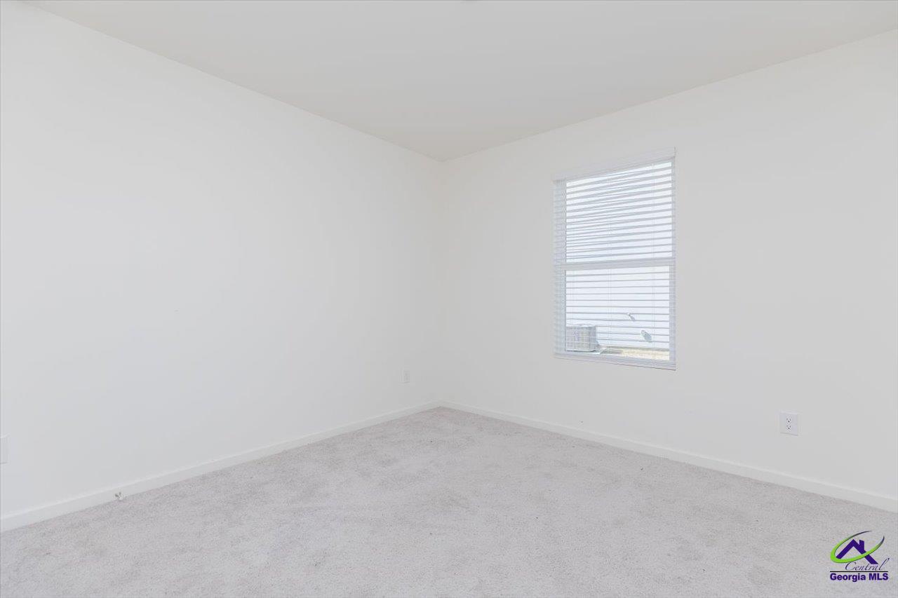 Empty bedroom with light gray carpet and a window with white blinds.